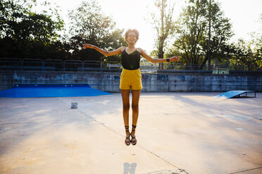 Junge Frau springt in einem Skatepark in die Luft - GIOF001408