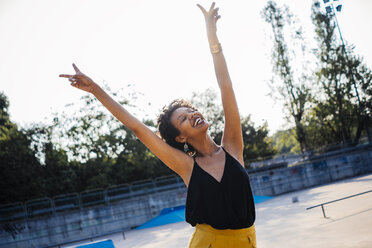 Happy young woman in a skatepark showing victory signs - GIOF001420