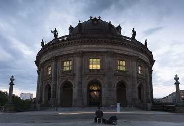 Deutschland, Berlin, Blick auf das beleuchtete Bode-Museum auf der Museumsinsel mit Straßenmusikanten im Vordergrund - FC001031