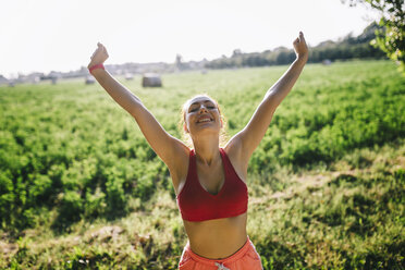 Italy, Tuscany, sportswoman raising arms - GIOF001453