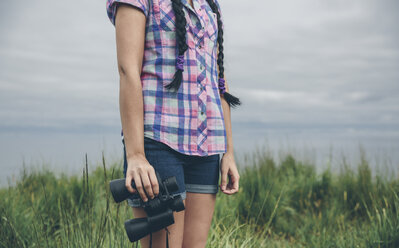 Woman in nature holding binocular, partial view - DAPF000254