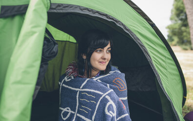 Smiling young woman sitting in a tent - DAPF000260