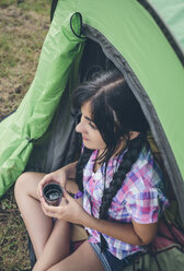 Junge Frau sitzt vor einem Zelt mit einer Tasse Kaffee - DAPF000263