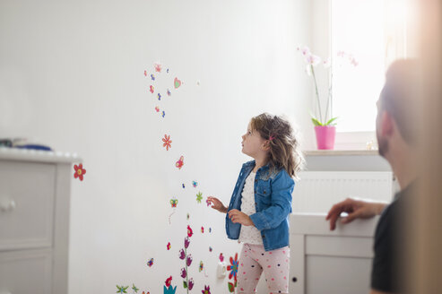 Mädchen betrachtet die dekorierte Wand im Kinderzimmer - DIGF000970