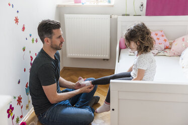 Vater zieht seiner Tochter die Socken an - DIGF000999