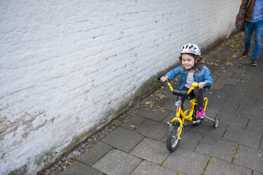 Tochter fährt Fahrrad mit Stützrädern - DIGF001005