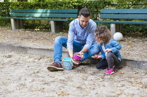 Vater spielt mit Tochter im Sandkasten - DIGF001013