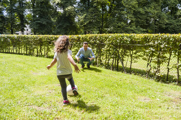 Father and daughter playing football in park - DIGF001021