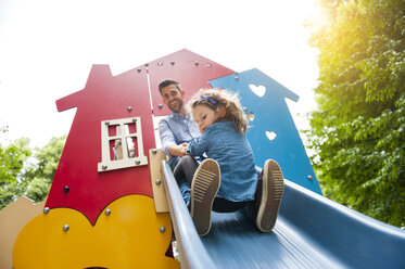 Vater mit Tochter auf Spielplatzrutsche - DIGF001027