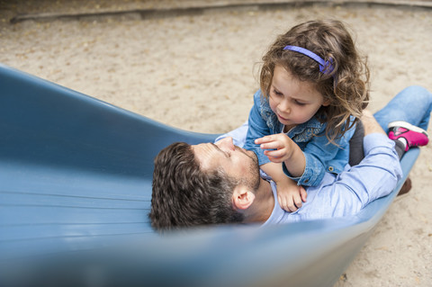 Vater mit Tochter auf Spielplatzrutsche, lizenzfreies Stockfoto