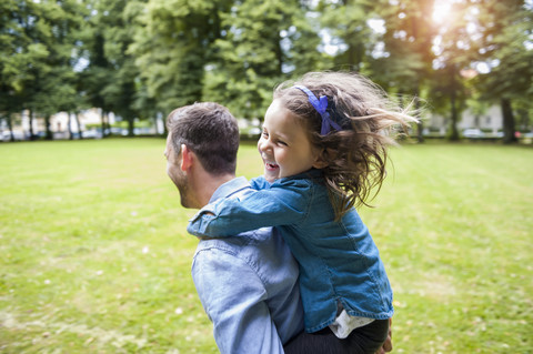 Vater trägt Tochter im Park auf den Schultern, lizenzfreies Stockfoto