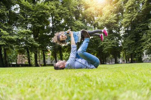 Vater und Tochter spielen auf einer Wiese im Park - DIGF001036