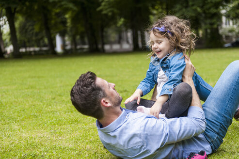 Vater und Tochter spielen auf einer Wiese im Park - DIGF001042