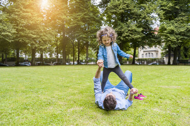 Vater und Tochter spielen auf einer Wiese im Park - DIGF001048