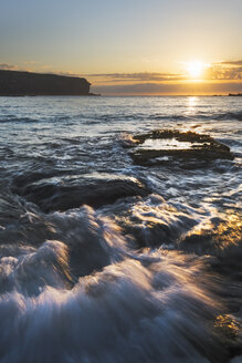 Australia, New South Wales, seascape with rushing water and rising sun and backlit, waves - GOAF000012
