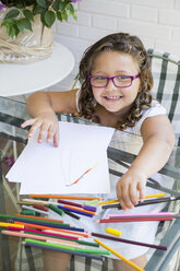 Portrait of smiling girl painting with coloured pencils - ABZF000973