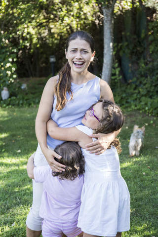 Mutter mit ihren kleinen Töchtern im Garten, lizenzfreies Stockfoto