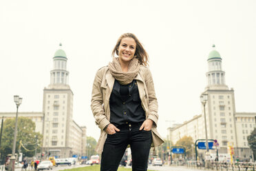 Germany, Berlin, portrait of smiling blond woman standing in front of Karl-Marx-Allee - TAMF000551