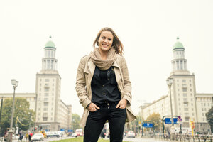 Deutschland, Berlin, Porträt einer lächelnden blonden Frau, die vor der Karl-Marx-Allee steht - TAMF000551