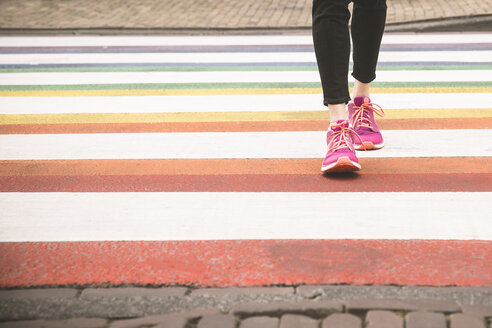 Woman crossing multi coloured zebra crossing, partial view - CHPF000287