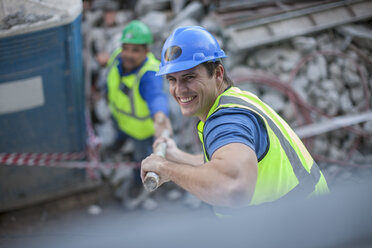 Lächelnder Bauarbeiter auf einer Baustelle - ZEF009434