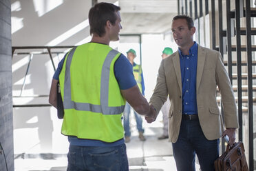 Two men shaking hands on construction site - ZEF009436