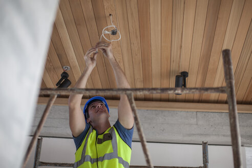 Elektriker befestigt Kabel an der Decke - ZEF009445