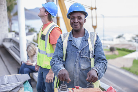 Lächelnder Bauarbeiter, der eine Maschine bedient, lizenzfreies Stockfoto