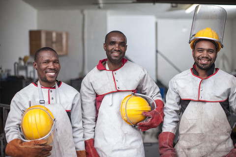 Porträt von drei lächelnden Arbeitern mit Schutzhelmen, lizenzfreies Stockfoto