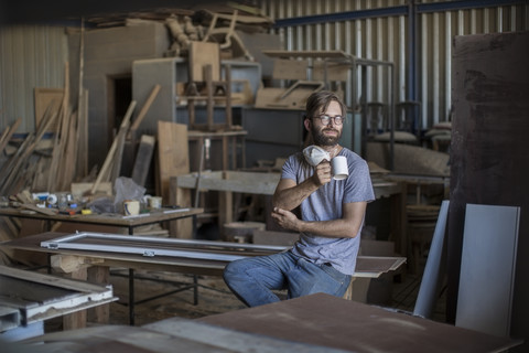 Carpenter drinking coffee in workshop stock photo