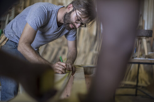 Zwei Schreiner messen ein Holzbrett in der Werkstatt aus - ZEF009544