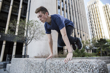 Spanien, Madrid, Mann springt während einer Parkour-Session über eine Mauer in der Stadt - ABZF000993