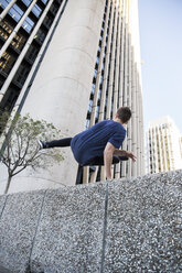 Spanien, Madrid, Mann springt während einer Parkour-Session über eine Mauer in der Stadt - ABZF000994