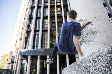 Spanien, Madrid, Mann springt während einer Parkour-Session über eine Mauer in der Stadt - ABZF000995