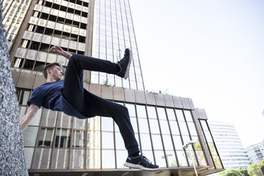 Spanien, Madrid, Mann springt während einer Parkour-Session über eine Mauer in der Stadt - ABZF000996