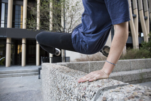 Spanien, Madrid, Mann springt während einer Parkour-Session über eine Mauer in der Stadt - ABZF000997