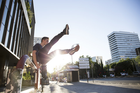 Spanien, Madrid, Mann springt während einer Parkour-Session über einen Zaun in der Stadt, lizenzfreies Stockfoto