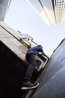 Spanien, Madrid, Mann klettert während einer Parkour-Session an einer Wand in der Stadt - ABZF001001