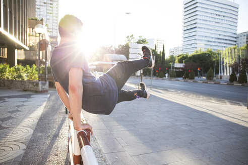 Spanien, Madrid, Mann springt während einer Parkour-Session über einen Zaun in der Stadt - ABZF001002