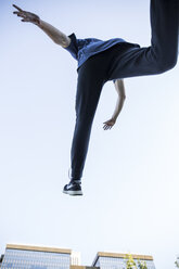 Spain, Madrid, man jumping in the city during a parkour session, low angle view - ABZF001003