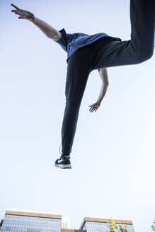 Spain, Madrid, man jumping in the city during a parkour session, low angle view - ABZF001003