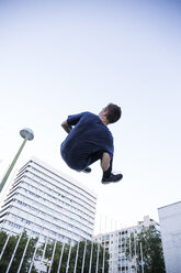 Spanien, Madrid, Mann springt in der Stadt während einer Parkour-Session, Tiefblick - ABZF001004