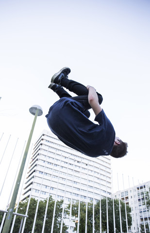 Spanien, Madrid, Mann springt während einer Parkour-Session über einen Zaun in der Stadt, lizenzfreies Stockfoto