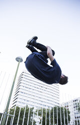 Spain, Madrid, man jumping over a fence in the city during a parkour session - ABZF001005