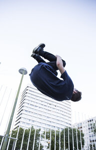 Spanien, Madrid, Mann springt während einer Parkour-Session über einen Zaun in der Stadt - ABZF001005