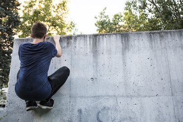 Spanien, Madrid, Mann klettert an einer Wand, während einer Parkour-Session - ABZF001006