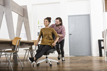 Man pushing happy woman on office chair - RBF004922