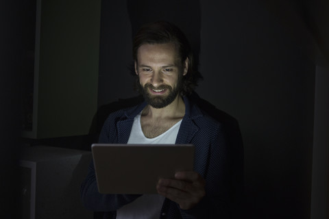 Mann benutzt digitales Tablet in der Dunkelheit, lizenzfreies Stockfoto