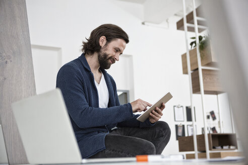 Mann benutzt digitales Tablet im Büro - RBF004928