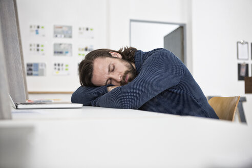 Mann schläft auf dem Schreibtisch im Büro - RBF004932